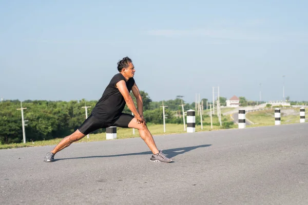 Erkek koşucu sabah koşuya hazırlanmak için bacak kasları germe. Sağlık ve fitness kavramı