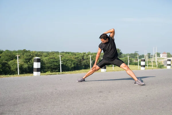 Erkek koşucu sabah koşuya hazırlanmak için bacak kasları germe. Sağlık ve fitness kavramı