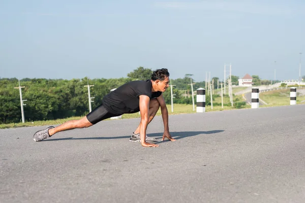 Erkek koşucu sabah koşuya hazırlanmak için bacak kasları germe. Sağlık ve fitness kavramı