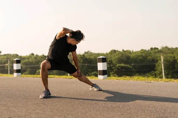 Erkek koşucu sabah koşuya hazırlanmak için bacak kasları germe. Sağlık ve fitness kavramı