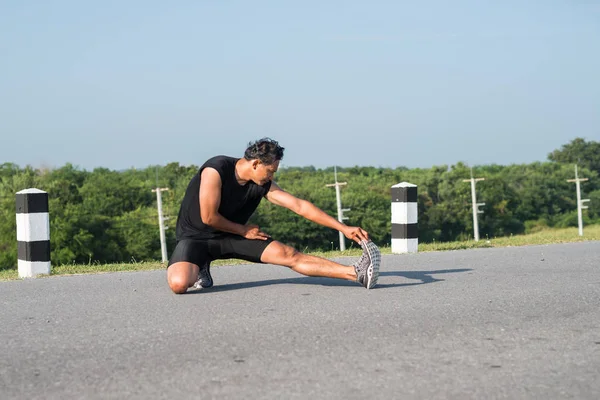 Erkek koşucu sabah koşuya hazırlanmak için bacak kasları germe. Sağlık ve fitness kavramı