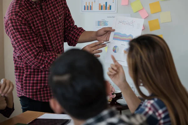 Odanın önünde dikilen sıradan ekose gömlekli genç Asyalı erkekler, konferansta başarılı bir iş yürütme konusunda meslektaşlarından geri bildirim istiyor. Takım çalışması iş toplantısı