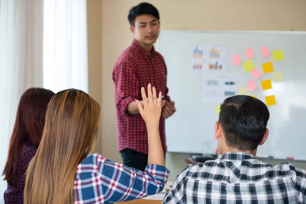 Sıradan ekose gömlek giyen Asyalı genç kadınların eli konferanstaki meslektaşlarından başarılı bir iş yürütme konusunda geri bildirim istiyor. Takım çalışması iş toplantısı