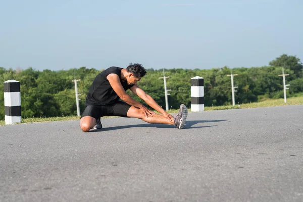 Erkek koşucu sabah koşuya hazırlanmak için bacak kasları germe. Sağlık ve fitness kavramı
