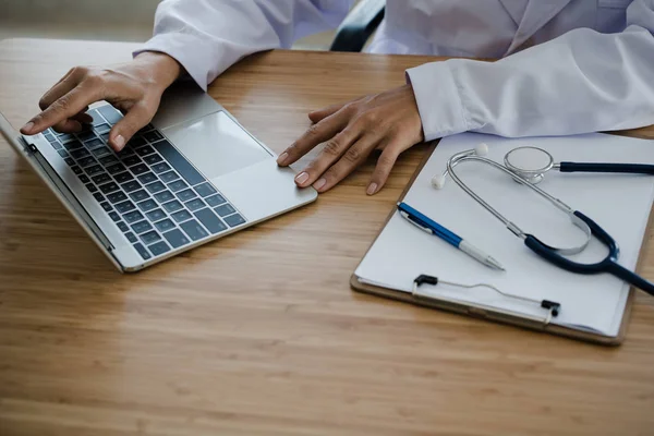 Genç doktor oturma çalışma masanın üstünde laptop ile