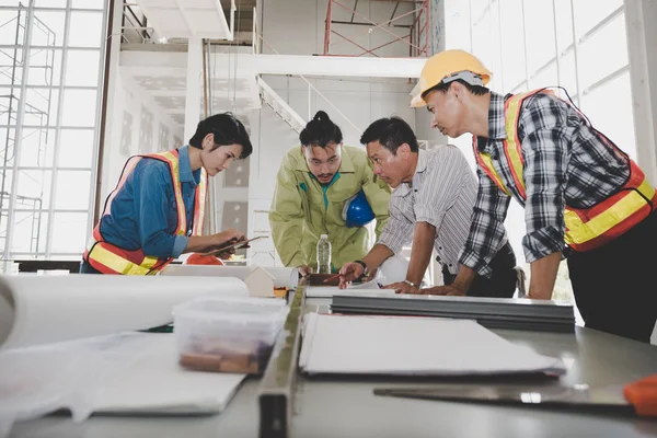 Bir grup erkek ve kadın mühendis bina inşaatı için planları hakkında konuşmak toplantı. ekip çalışması kavramı