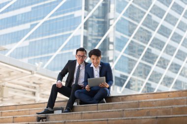 Asyalı iki işadamı dizüstü bilgisayarı izlerken mutlu oluyor. iş bölgesi arka planında