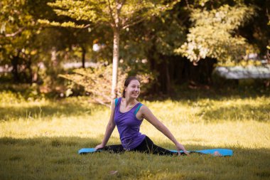 Pratik yoga açık parkta gülümseme bir genç kadın. Sağlıklı yaşam tarzı ve gevşeme kavramı.