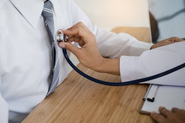 Bir hasta stetoskop tıbbi ofis ile inceleyerek doktor el