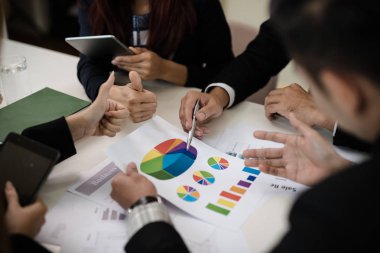 Bir grup iş adamı ve kadın iş pazarlama satış hedefinin grafiklerini görmek için bir araya geliyor. Takım çalışması iş toplantısı kavramı