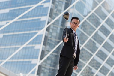 Takım elbiseli başarılı bir iş adamı. golf ekipmanları kentin ayakta tutan el. Şehir arka plan başarı kavramı