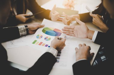 Bir grup iş adamı ve kadın iş pazarlama satış hedefinin grafiklerini görmek için bir araya geliyor. Takım çalışması iş toplantısı kavramı