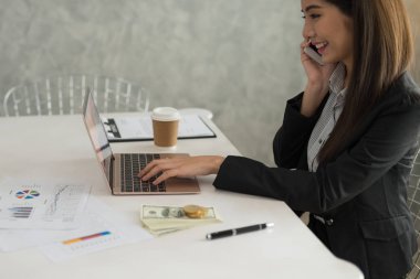 Laptop çalışma güzel Asyalı Genç iş kadını olmak gülümseme telefon onun iş istasyonu