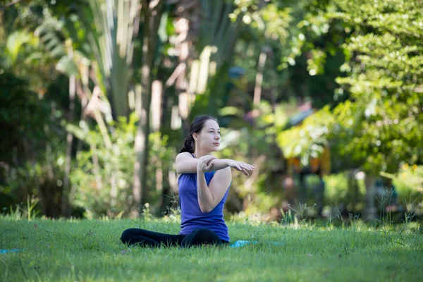 Parkta yoga yapan genç bir kadın. Sağlıklı yaşam tarzı ve rahatlama kavramı.