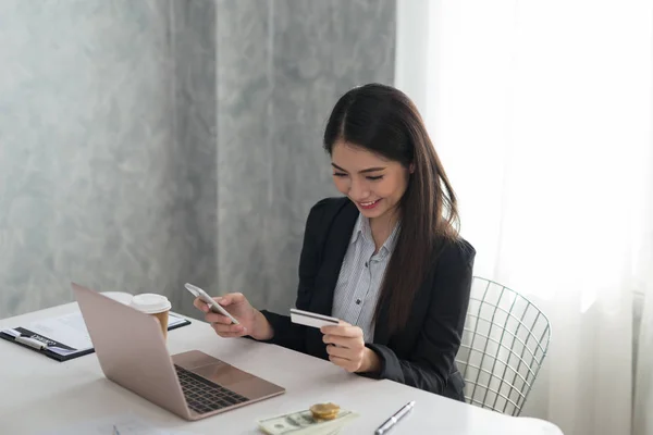 Beautiful asian young businesswoman holding phone and credit card  buying on line. Online shopping, technology concept