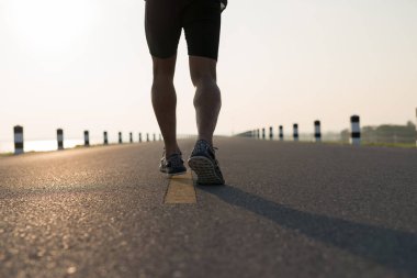 Gündoğumu sırasında verilen sürede baraj yolu üzerinde çalışan bir adam Asya bacaklar görünümünü aşağı egzersiz. Sağlıklı yaşam tarzı