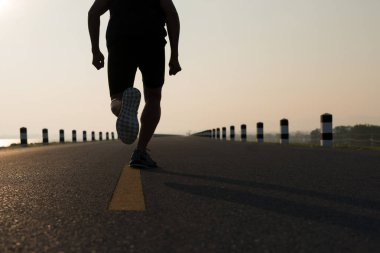 Gündoğumu sırasında verilen sürede baraj yolu üzerinde çalışan bir adam Asya bacaklar görünümünü aşağı egzersiz. Sağlıklı yaşam tarzı