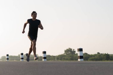 Asya genç adam gündoğumu dönemde baraj yolu egzersiz üzerinde çalıştırmak için. Sağlıklı yaşam tarzı