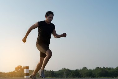 Asya genç adam gündoğumu dönemde baraj yolu egzersiz üzerinde çalıştırmak için. Sağlıklı yaşam tarzı