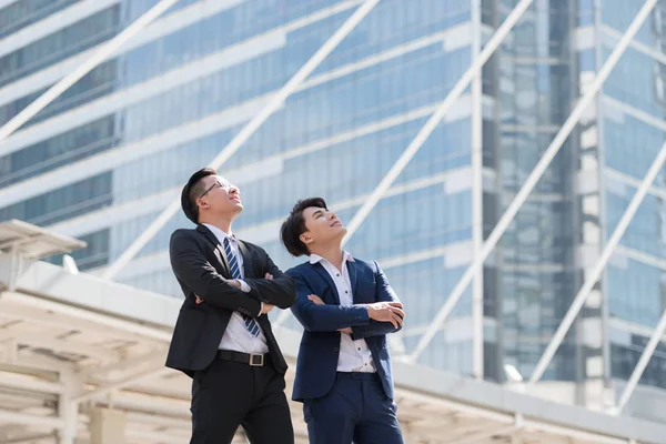 Takımlı ellerle şehirde ayakta başarılı iki iş adamı göğsünde, gitmek büyük şehir binaları, Toplantı başlatmak bekleyen yeni projelerin planlanması seyir geçti. Metin için yer kopyalayın