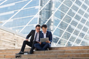 Asyalı iki işadamı dizüstü bilgisayarı izlerken mutlu oluyor. iş bölgesi arka planında