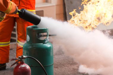 Nasıl bir yangın söndürücü kullanılacağını gösteren eğitmen. Gaz tankları ile ateş. Eğitim sırasında