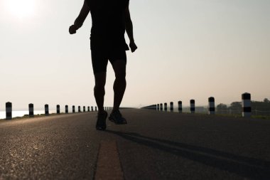 Gündoğumu sırasında verilen sürede baraj yolu üzerinde çalışan bir adam Asya bacaklar görünümünü aşağı egzersiz. Sağlıklı yaşam tarzı