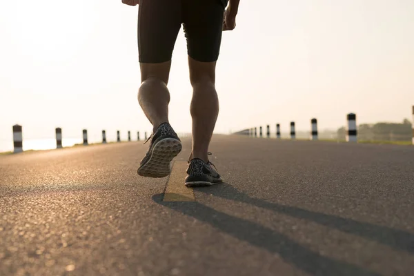 Down view of a man asia legs running in the time during sunrise on dam road exercise.Healthy lifestyle