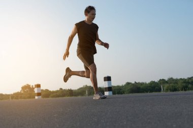 Asya genç adam gündoğumu dönemde baraj yolu egzersiz üzerinde çalıştırmak için. Sağlıklı yaşam tarzı