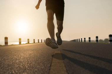 Asya genç adam gündoğumu dönemde baraj yolu egzersiz üzerinde çalıştırmak için. Sağlıklı yaşam tarzı