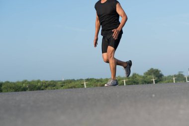 Gündoğumu sırasında verilen sürede baraj yolu üzerinde çalışan bir adam Asya bacaklar görünümünü aşağı egzersiz. Sağlıklı yaşam tarzı