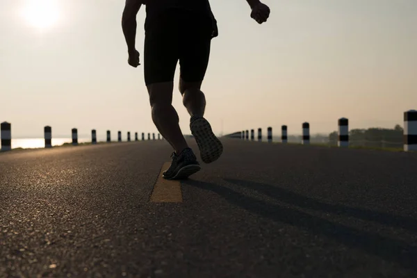 Down view of a man asia legs running in the time during sunrise on dam road exercise.Healthy lifestyle