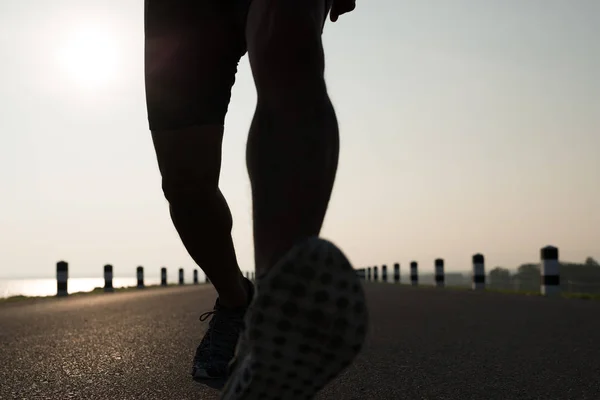 Down view of a man asia legs running in the time during sunrise on dam road exercise.Healthy lifestyle