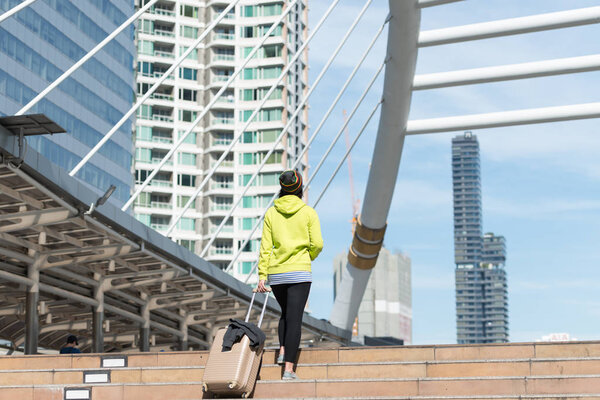Обратный вид женщины турист с чемоданом во время ходьбы по лестнице в здании города, концепция путешествия
