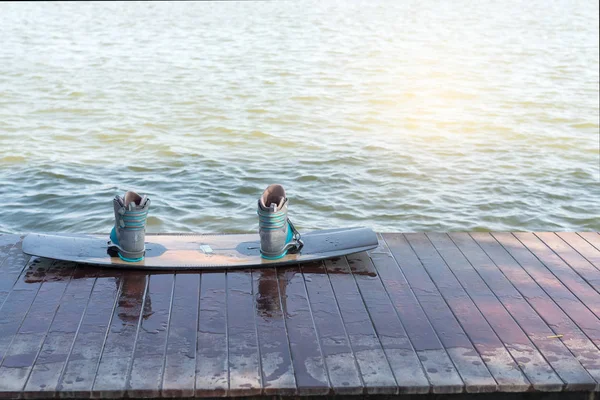Wakeboarding boots and board, water sport objects, on wooden floor