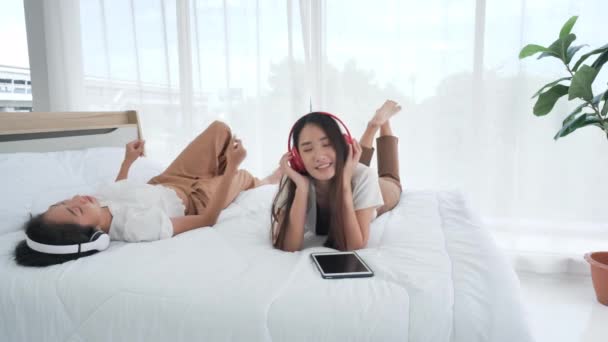 Két Ázsiai Tinédzser Lány Boldogan Fülhallgatózik Digitális Táblagéppel Miközben Otthon — Stock videók