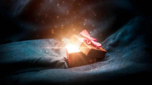 Gift box on a dark magic background with light bokeh. Festive background, magic box with a gift. Dark abstract background with gold bokeh.