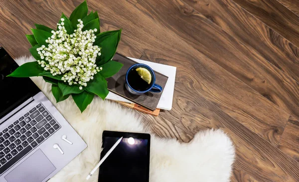 Wooden tray on a blue bed. Work at home. Cup of tea on a tray with a flower. Tablet and phone on the bed. Beautiful modern neoclassical interior.