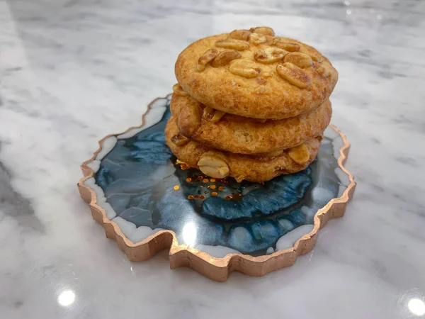 Sugar glazed cookies with peanuts on a blue marine epoxy tray on a marble table.