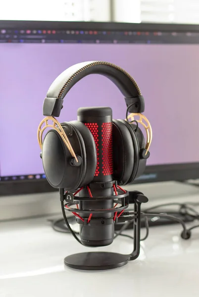 Gaming headphones and microphone with red neon lighting. Gaming devices on a white glossy table. Gamezone, lifestyle.