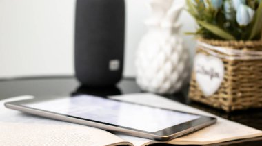 Cam bir sehpanın üzerinde açık bir dergi ve tablet. Bulanık bokeh arka plan, yakın plan. Güneş ışığı, gün batımı, bokeh.