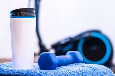 Spor geçmişi, mavi aksanlı dambıl, cam, havlu, elepsoid. Spor aktiviteleri. Evde spor, spor için özellikler. Etkin yaşam biçimi.