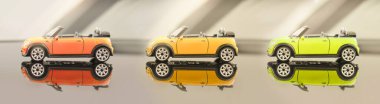 Üstü açık sarı renkli gri arka planda Mini Cooper. Sarı bir oyuncak araba arka planda, aynalı bir zemine yansıyor. 31 Temmuz 2020, Belarus Gomel.
