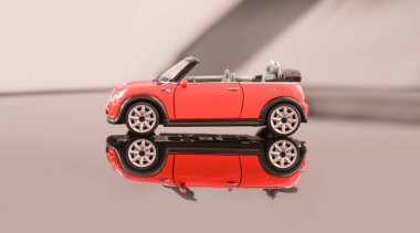 Üstü açık sarı renkli gri arka planda Mini Cooper. Sarı bir oyuncak araba arka planda, aynalı bir zemine yansıyor. 31 Temmuz 2020, Belarus Gomel.