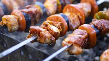 Dışarıdaki ızgarada şiş kebap, kömürde et, yakın plan. Duman, bulanık arka plan. Pelerin, domates, patlıcan, soğan.