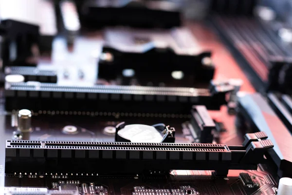 Computer motherboard with small parts, components for computer assembly and repair. Tech background, neon light. Close-up.