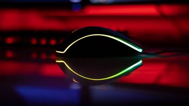 Beyaz parlak bir masa üzerinde neon ışıklı bilgisayar faresi, karanlık oda, neon ışık, diyotlar. Oyun aletleri, neon ışıklar, beyaz parlak masa. Yaşam tarzı, oyun alanı.
