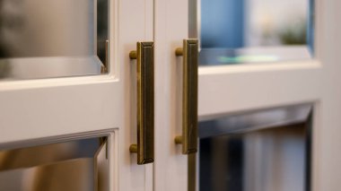 Aynalı beyaz gardırop, sallanan kapılar, bronz saplar, yakın çekim. Neoklasik mobilyalar. Klasik oturma odası..