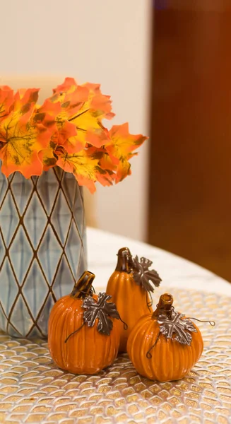 Halloween background with pumpkins. Decorative pumpkins for setting the festive table. Orange pumpkins, cobwebs, autumn leaves in a vase.