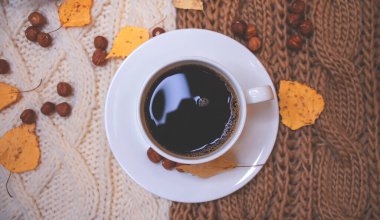 Sonbahar arkaplanı, kahve, örgü eşarp, balkabağı. Sonbahar kahvesi, kuru yapraklar. Sezon Ekim, Kasım.